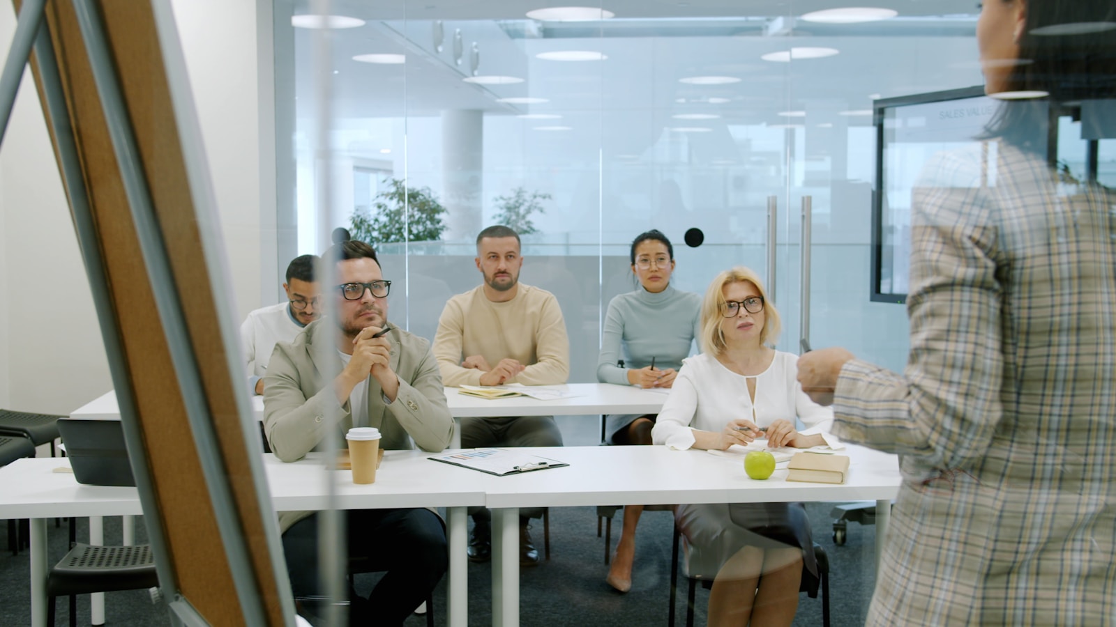 Back view of business expert ambitious woman talking to multi-ethnic group of people in office speaking and gesturing discussing marketing and sales planning.